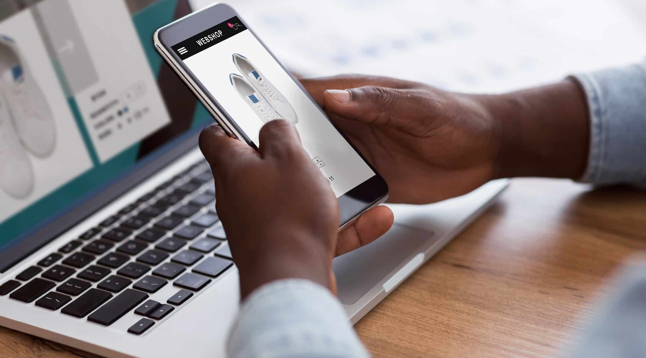 Man compares item on desktop to mobile phone.